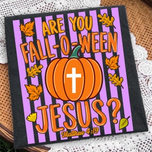 May include: A black t-shirt featuring a graphic print with vertical purple and black stripes. The design includes an orange pumpkin with a white cross, surrounded by yellow autumn leaves, and the text ARE YOU FALL-O-WEEN JESUS? Matthew 4:19.