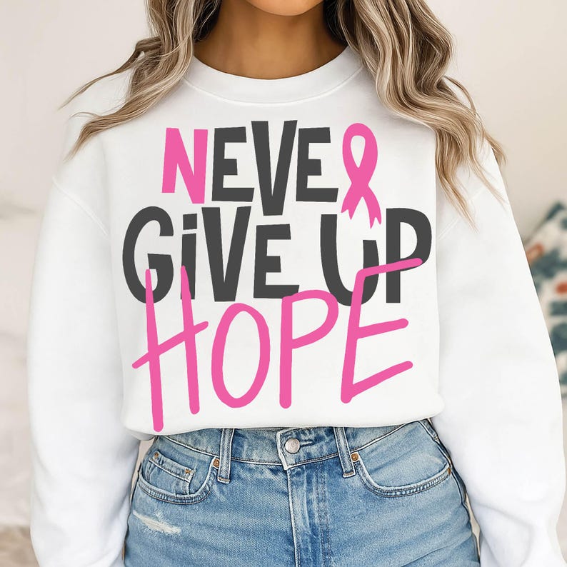 May include: White sweatshirt with the words "NEVER GIVE UP HOPE" in black and pink lettering. A pink ribbon graphic is incorporated into the design. The sweatshirt is a casual style.