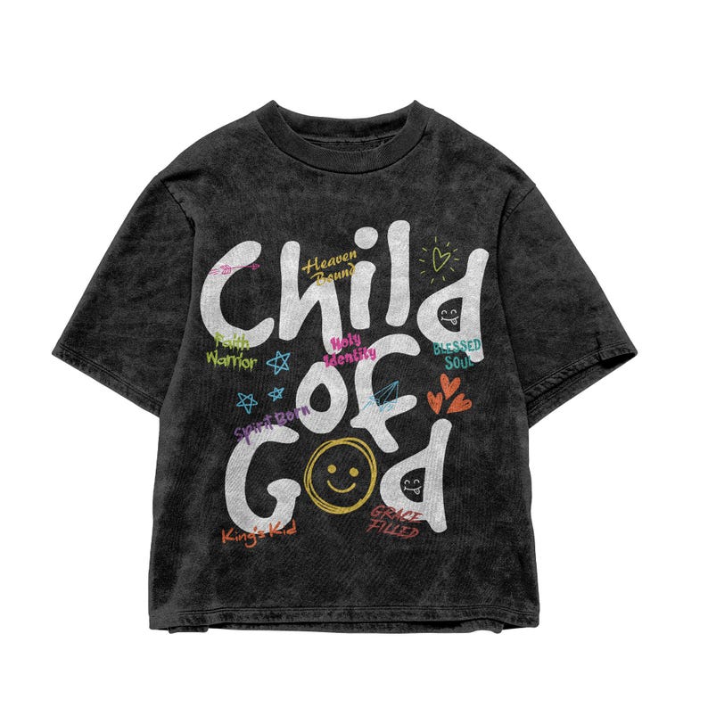 Dark washed black t-shirt shown in a flat lay product mockup against a white background, displaying large white “Child of God” text with playful Christian-themed words, hearts, stars, and graphic accents. The isolated product image clearly presents the vibrant faith-based shirt design for online listings.