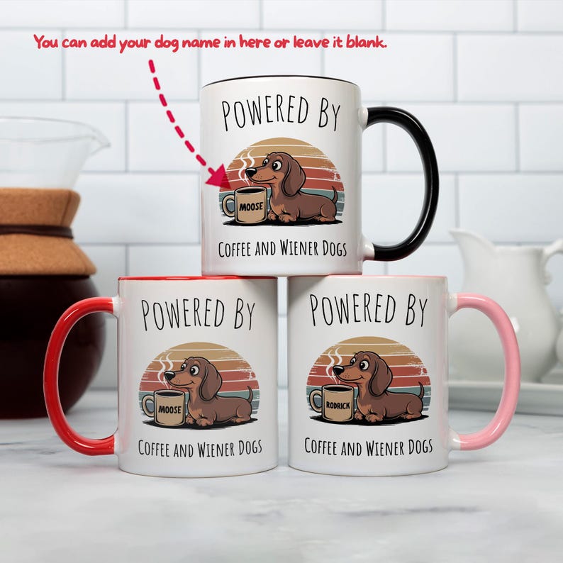 May include: White ceramic mugs with colorful accents and a dachshund design. The mugs feature the text "POWERED BY" above a cartoon dachshund with a coffee mug. The text "COFFEE AND WIENER DOGS" is below the dog. One mug has a black handle, one has a red handle, and one has a pink handle.