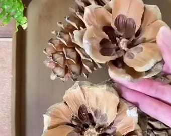 May include: Close-up of several large pine cones, some with petals painted in shades of tan and brown. The pine cones are arranged on a gold-colored tray. The image highlights the natural textures and colors of the pine cones.