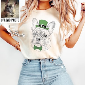 May include: Cream-colored t-shirt featuring a detailed sketch of a French Bulldog wearing a green top hat and bow tie. The image includes a small photo with the text "UPLOAD PHOTO" in a black box. The dog illustration is in black and white.