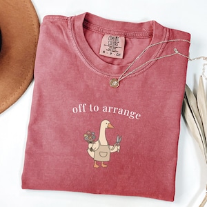 Comfort Colors t-shirt with "off to arrange" and a person holding flowers and scissors.