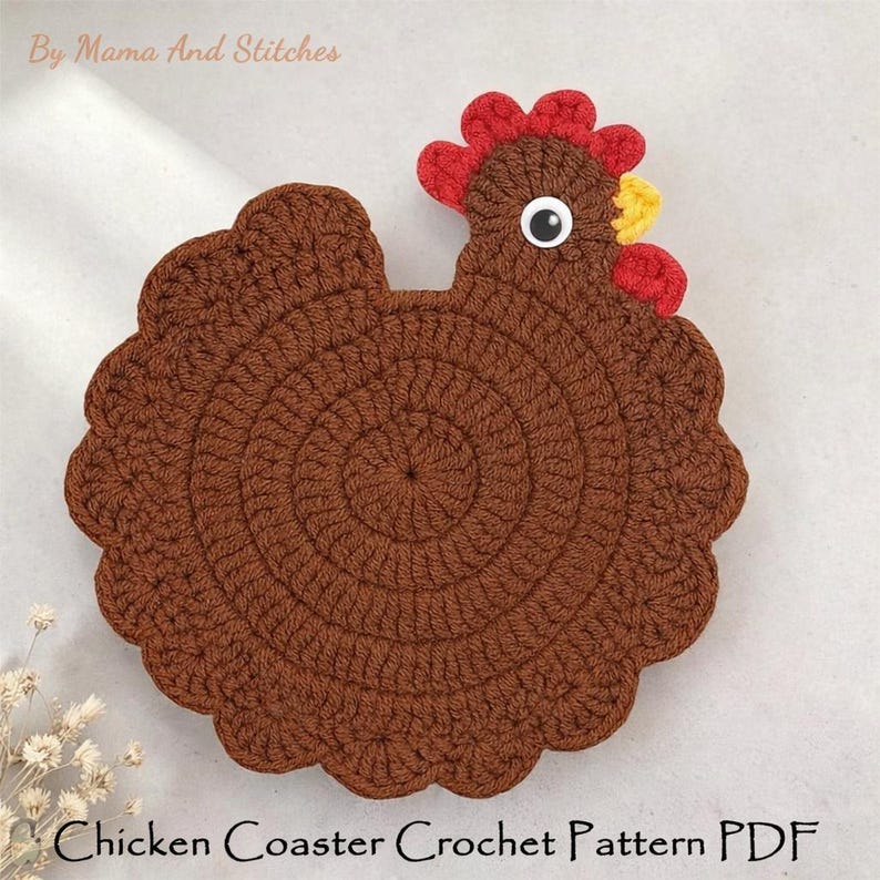 Pode incluir: Um porta-copos de croch&ecirc; em formato de galinha marrom com crista e barbelas vermelhas, bico amarelo e um olho preto e branco. O texto "By Mama And Stitches" e "Chicken Coaster Crochet Pattern PDF" est&aacute; vis&iacute;vel na imagem do produto.