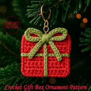 May include: A red crochet gift box ornament with a green bow and ribbon detail. The ornament is suspended by a gold-colored keyring. The text "Crochet Gift Box Ornament Pattern" is at the bottom, and "CROCHET PATTERN" is in a circle on the left.