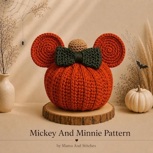 May include: A crocheted orange pumpkin with two large round orange ears, a dark green bow, and a small tan stem on top. The text "Mickey And Minnie Pattern" and "by Mama And Stitches" is printed at the bottom of the image.