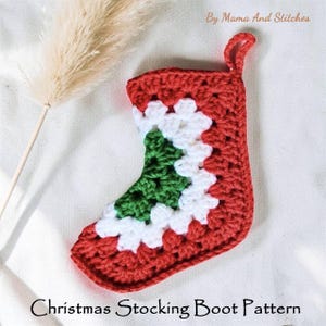 Puede incluir: Un patrón de bota de calcetín navideño de ganchillo rojo, blanco y verde hecho a mano. El calcetín presenta un diseño de árbol de Navidad en el centro. El texto "Christmas Stocking Boot Pattern" está en la parte inferior. El texto "By Mama And Stitches" está en la parte superior.