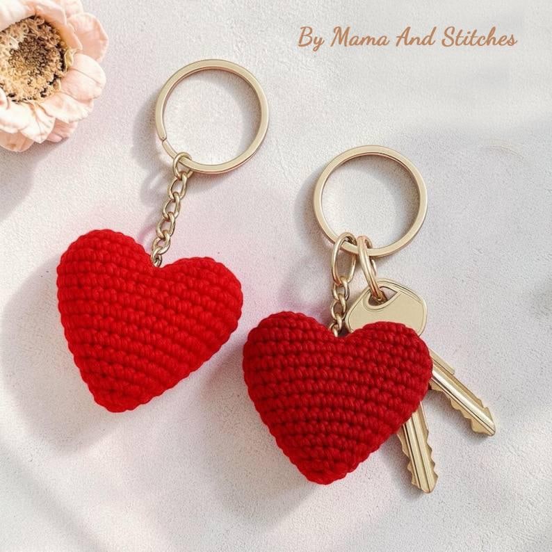 Peut inclure: Deux porte-cl&eacute;s en forme de c&oelig;ur rouge crochet&eacute; avec des anneaux et des cha&icirc;nes dor&eacute;s. Un porte-cl&eacute;s a deux cl&eacute;s attach&eacute;es. Le texte "By Mama And Stitches" est dans le coin sup&eacute;rieur droit.