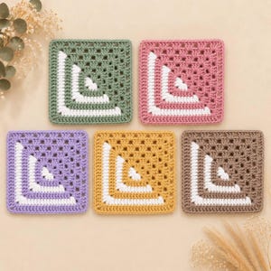 May include: Five square crochet coasters arranged in a group. Each coaster features a granny square pattern with a solid color border in sage green, dusty pink, lavender, mustard yellow, or taupe, accented by two white L-shaped corner stripes.