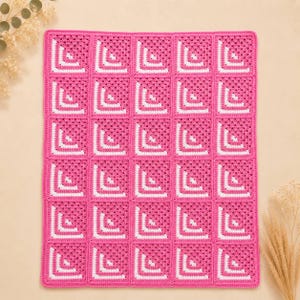 May include: A rectangular crochet blanket composed of thirty individual square motifs. Each square features a vibrant hot pink base with a white L-shaped corner accent. The squares are joined together in a grid pattern to form a cohesive textile piece.