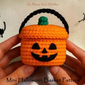 May include: A crocheted orange mini Halloween basket with a black handle and a green stem. The basket has a jack-o'-lantern face. The text "Mini Halloween Basket Pattern" is at the bottom of the image.