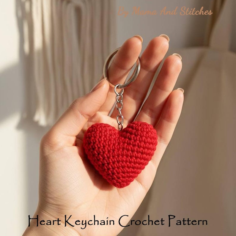 Peut inclure: Un porte-cl&eacute;s en forme de c&oelig;ur rouge crochet&eacute;. Le charm en forme de c&oelig;ur est attach&eacute; &agrave; un porte-cl&eacute;s de couleur argent&eacute;e avec une cha&icirc;ne. Le texte "Heart Keychain Crochet Pattern" est au bas de l'image.