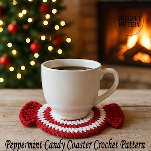 May include: A white ceramic mug filled with coffee sits on a red and white peppermint candy-shaped crochet coaster. The coaster is handmade and has a circular design. The text "Peppermint Candy Coaster Crochet Pattern" is at the bottom.