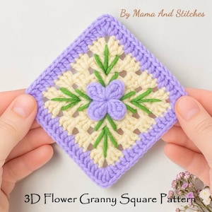 May include: A square, crocheted granny square with a 3D flower design. The square features a light purple border, a cream-colored center, and a light purple flower with green leaves. The text "By Mama And Stitches" and "3D Flower Granny Square Pattern" are visible.