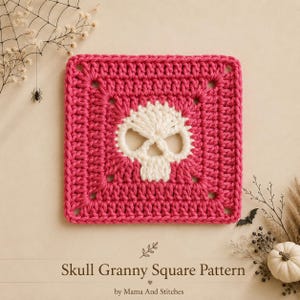 May include: A square crochet piece featuring a hot pink border and a central white skull motif. The text below reads Skull Granny Square Pattern by Mama And Stitches. The design is a flat, hand-stitched textile square with a clear, repeating pattern.