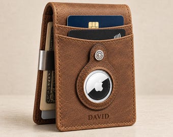May include: A brown leather wallet featuring a dedicated circular slot for an Apple AirTag, a metal money clip on the side, and two card slots. The name DAVID is embossed on the front, and the wallet contains paper currency and two cards.