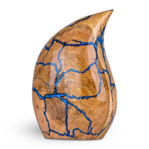 May include: A teardrop-shaped wooden sculpture with a polished finish. The wood grain is visible, and the piece is accented with vibrant blue resin that fills the cracks, creating a striking contrast. The sculpture has a smooth, curved form.