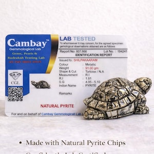 May include: A metallic pyrite turtle figurine with a detailed shell, next to a lab report. The report indicates a weight of 91.00 grams and a refractive index of 1.81. The figurine is a compact, elegant decor piece.