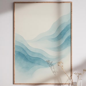 May include: A framed art print featuring an abstract watercolor design. The artwork showcases layered, flowing blue and teal hues against a cream background. The wooden frame adds a natural touch to the piece, suitable for home decor.
