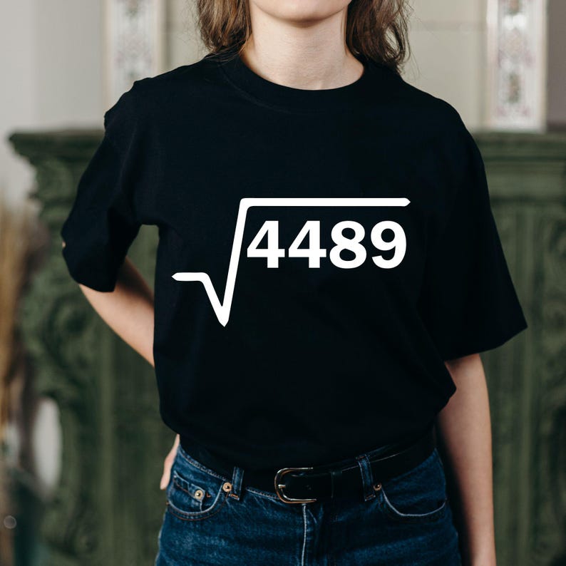 K&ouml;nnte beinhalten: Schwarzes T-Shirt mit wei&szlig;er Grafik eines Quadratwurzelsymbols und der Zahl 4489. Das T-Shirt hat einen Rundhalsausschnitt. Die Person, die das Shirt tr&auml;gt, tr&auml;gt auch eine blaue Jeans und einen schwarzen G&uuml;rtel.