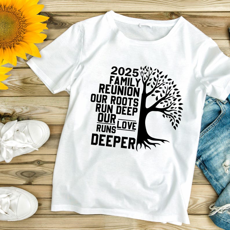 May include: White t-shirt with a black graphic of a tree and the text "2025 Family Reunion Our Roots Run Deep Our Love Runs Deeper." The shirt is laid flat on a wooden surface with a sunflower and white sneakers.