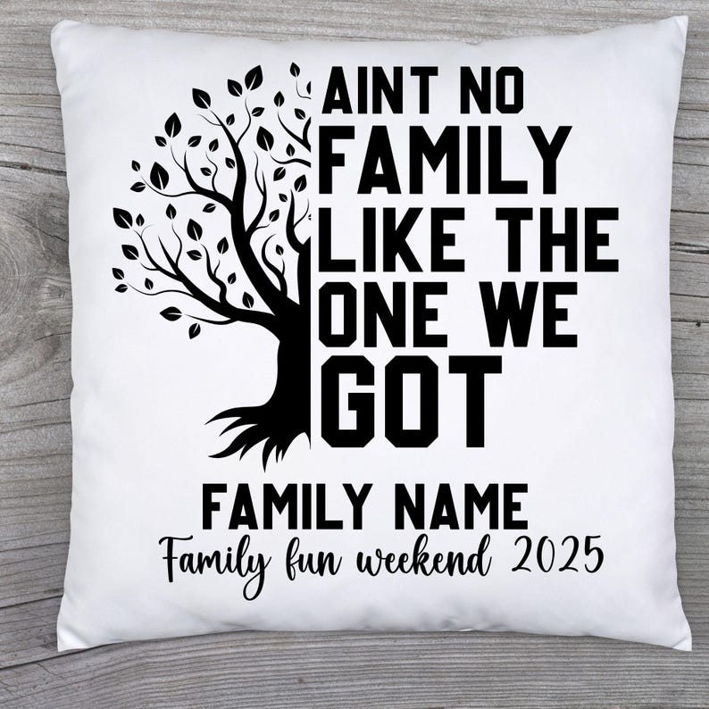 May include: White square pillow with a black tree graphic and the text "AINT NO FAMILY LIKE THE ONE WE GOT." Below the text is "FAMILY NAME" and "Family fun weekend 2025" in a script font.