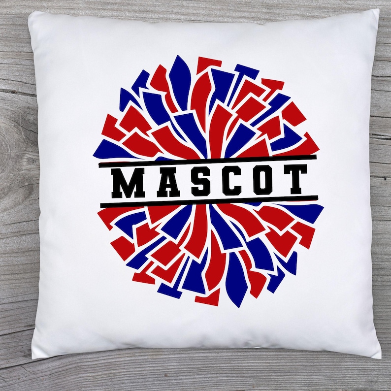 May include: White square pillow with a red, blue, and black pom-pom design. The word "MASCOT" is printed in bold black letters across the center of the pom-pom. The pillow is likely a decorative item.