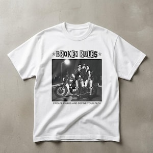 May include: White t-shirt featuring a black and white image of two people on a motorcycle. The text "BROKEN RULES" is above the image, with the phrase "CREATE CHAOS AND DEFINE YOUR PATH" below.