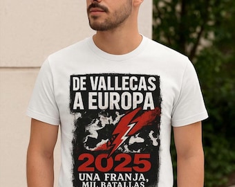 May include: White t-shirt with a graphic design. The design includes the text "DE VALLECAS A EUROPA 2025 UNA FRANJA, MIL BATALLAS" in black and red, along with a red lightning bolt. The shirt is worn by a person.