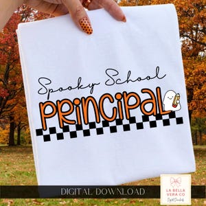 May include: A white t-shirt featuring the black text Spooky School, with the word PRINCIPAL in large orange letters below it. A small white ghost character holding a yellow pencil is next to the text, above a black and white checkerboard pattern.