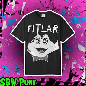 May include: Black t-shirt with the word "FITLAR" in white block letters above a cartoon frog face with spiral eyes and a bow tie. The shirt is set against a pink and black background with the text "SBW PUNK" at the bottom.