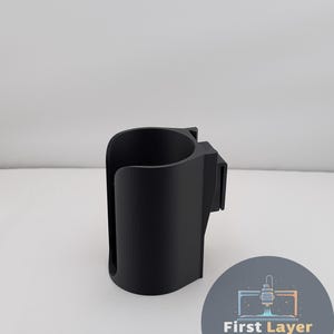 May include: A black 3D-printed cup holder with a curved design and a mounting clip. The cup holder is designed to hold a standard-sized beverage container. The image also includes a circular logo with the text "First Layer FANATICS".