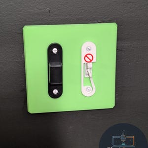 May include: A bright green light switch cover with a black toggle switch and a white safety device. The safety device has a red circle with a line through it, indicating it is disabled. The logo "First Layer Fanatics" is in the bottom right corner.