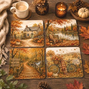 May include: A set of four square coasters featuring autumn-themed illustrations: a stone cottage, a lakeside bench, a wooden bridge with a sign reading Be Grateful, Be Kind, Be Thankful, and a bicycle with a basket and a sign reading hello AUTUMN.