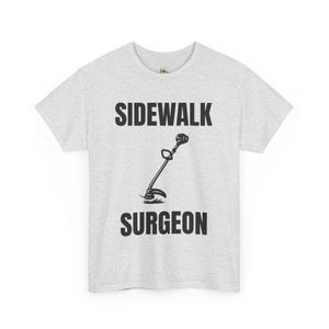 May include: Light gray t-shirt with the words "SIDEWALK SURGEON" in black block letters. A black and white illustration of a string trimmer is centered between the words. The shirt is made of a soft, comfortable material.