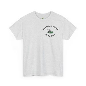 Peut inclure: T-shirt gris clair à col rond. Le t-shirt présente un petit motif de tondeuse à gazon et le texte "Your Wife Is Staring At My Grass" dans un design circulaire.