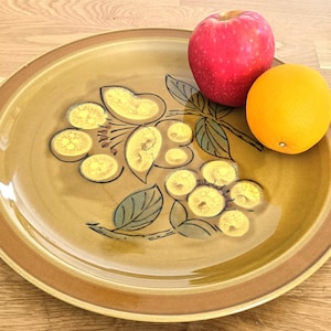 Puede incluir: Una taza de cerámica blanca con un asa negra y el texto "But First, Coffee" en un estilo manuscrito. La taza está sobre una superficie blanca. La taza se utiliza probablemente para bebidas calientes.