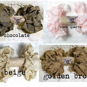May include: Four fabric flower arrangements in chocolate, rose quartz, beige, and golden brown. Each arrangement is centered on a decorative cork with the text "Wicked Pixie" and a small image. The colors are displayed on a white lace background.