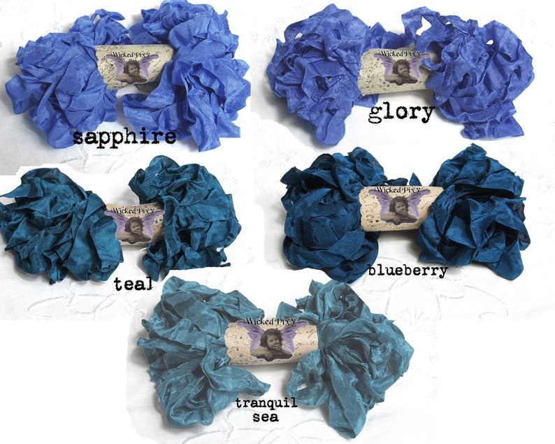 May include: Five bundles of ruffled fabric ribbon in shades of blue and teal. The colors are sapphire, glory, teal, blueberry, and tranquil sea. Each bundle has a decorative tag with the text "Wicked Pixy".