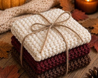 May include: A stack of three square crocheted washcloths in cream, burgundy, and brown, tied together with thin brown twine. The top washcloth is cream, the middle is burgundy, and the bottom is brown. The text Fall Harvest is visible.