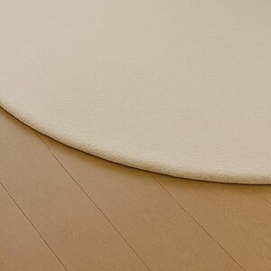 A modern white round rug placed in a beige living room beside large windows with pool and garden view. The soft wool-blend carpet sits under a marble coffee table and cream sofa, creating a bright, elegant, and minimalist interior. Perfect for contemporary, Scandinavian, or neutral-style homes.