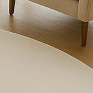 A modern white round rug placed in a beige living room beside large windows with pool and garden view. The soft wool-blend carpet sits under a marble coffee table and cream sofa, creating a bright, elegant, and minimalist interior. Perfect for contemporary, Scandinavian, or neutral-style homes.