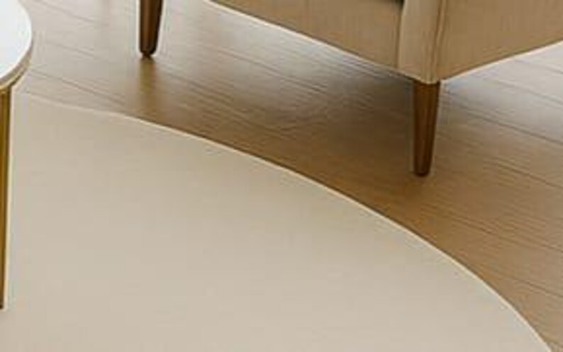 A modern white round rug placed in a beige living room beside large windows with pool and garden view. The soft wool-blend carpet sits under a marble coffee table and cream sofa, creating a bright, elegant, and minimalist interior. Perfect for contemporary, Scandinavian, or neutral-style homes.