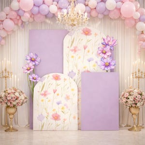Peut inclure: Un décor de fond pour une célébration aux tons pastel. La scène comprend une arche de ballons roses et violets, des panneaux floraux et un lustre. Des candélabres dorés et des compositions florales ajoutent de l'élégance à l'ensemble.