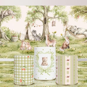 Pode incluir: Três pedestais cilíndricos com padrões em verde claro e branco, incluindo xadrez vichy, coroas florais com uma ilustração de urso e listras verticais com pequenos insetos, contra um fundo de uma cena de floresta com animais.