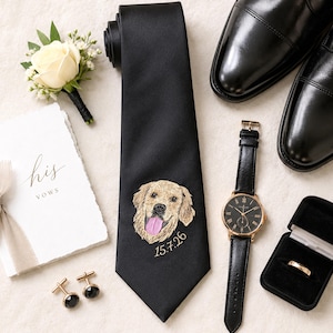 Könnte beinhalten: Eine schwarze Krawatte mit einem gestickten Golden Retriever Porträt und dem Datum 15.7.26, begleitet von einem weißen Rosen-Ansteckblümchen, schwarzen Anzugschuhen, einer Uhr mit schwarzem Lederarmband, Manschettenknöpfen und einem Ring.