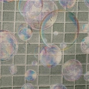 May include: Fabric with a repeating pattern of iridescent bubbles in shades of purple, blue, and green. The bubbles are scattered across a light green, grid-patterned background, creating a whimsical and playful design.