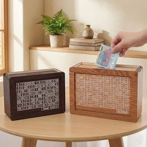 Puede incluir: Dos huchas de madera con un patrón de cuadrícula. Una caja es de color marrón oscuro con una cuadrícula blanca y el texto "Total: 1000€". La otra caja es de color marrón claro con una cuadrícula y el texto "10.000 €".