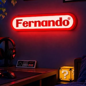 May include: A rectangular wall-mounted LED sign with a red border and white background, featuring the name Fernando in a bold, black, sans-serif font. The sign is illuminated with a bright red glow, creating a vibrant light effect on the wall.