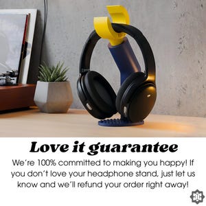 K&ouml;nnte beinhalten: Schwarzer Over-Ear-Kopfh&ouml;rer auf einem blau-gelb-schwarzen Kopfh&ouml;rerst&auml;nder. Der St&auml;nder steht auf einer Holzoberfl&auml;che. Das Bild enth&auml;lt den Text "Love it guarantee".